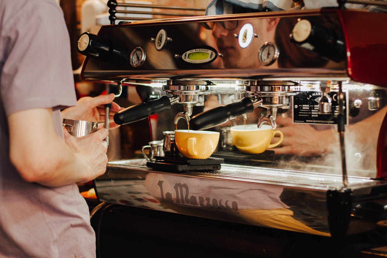 why-choose-us Barista using espresso machine to brew coffee in a café, showcasing coffee preparation process.