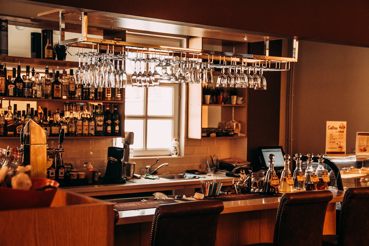 services-03 A stylish bar interior featuring hanging glassware, a range of spirits, and wooden furnishings.